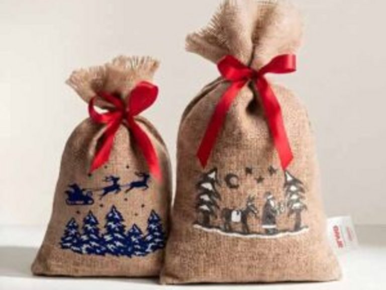 Zwei traditionelle Chlaussäcke aus Jute mit roten Schleifen und weihnachtlichen Motiven.