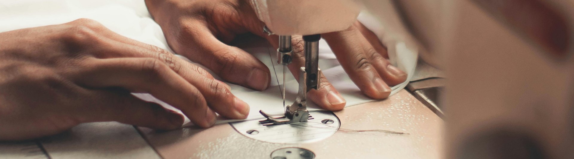 Arbeiten im Nähatelier: Hände an der Nähmaschine.